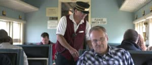 Conductor Kelly welcomes guest on board as he punches tickets.