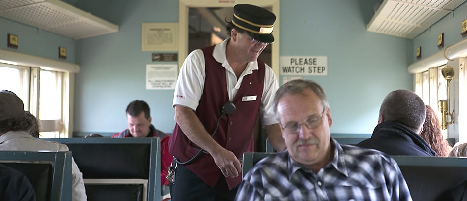 Conductor Kelly welcomes guest on board as he punches tickets.